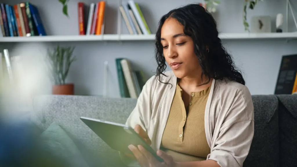 Woman looking at her ipad while sitting on her couch in a living room